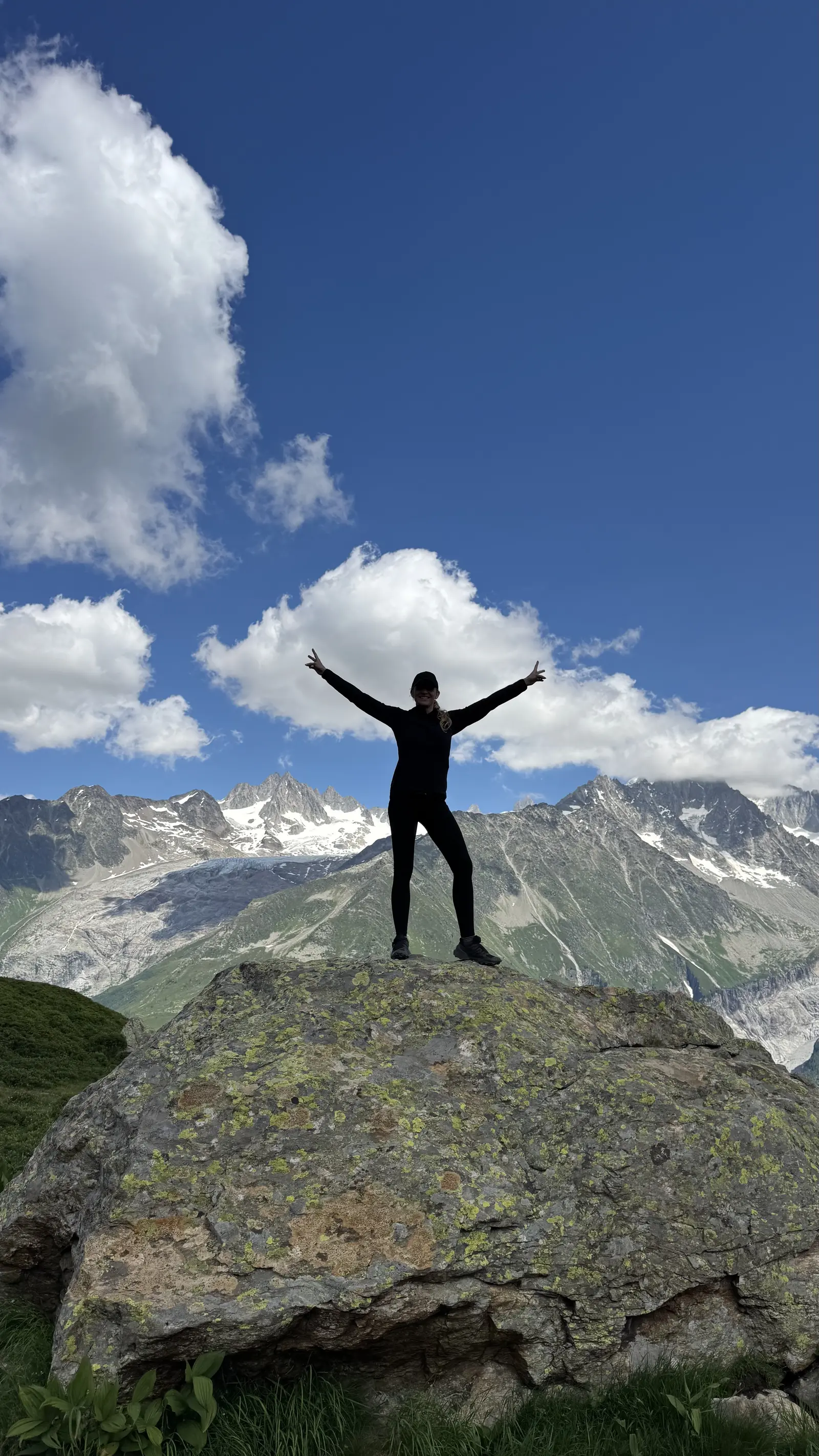 Henriette standing with open arms on a mountain rock