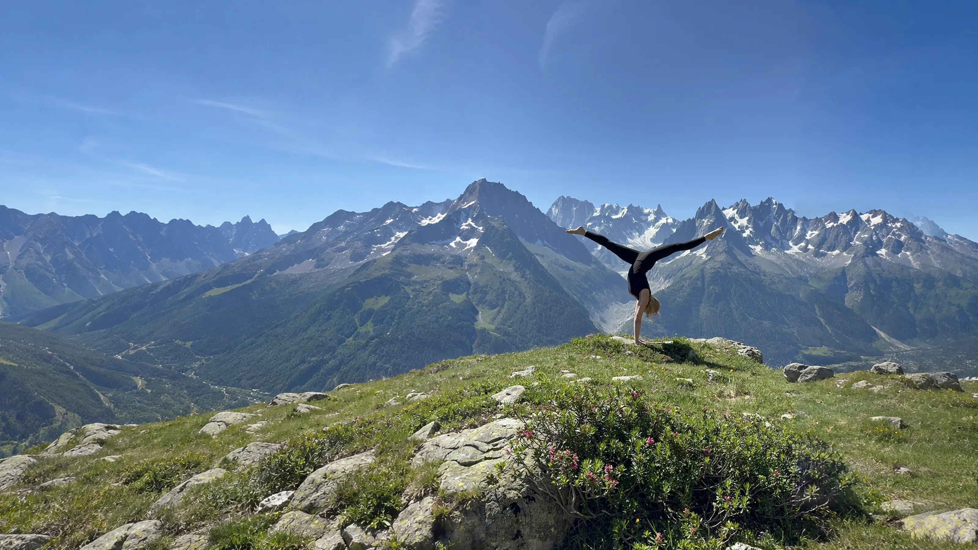 Henriette Aluma Nedergaard holding an open split handstand in the mountains